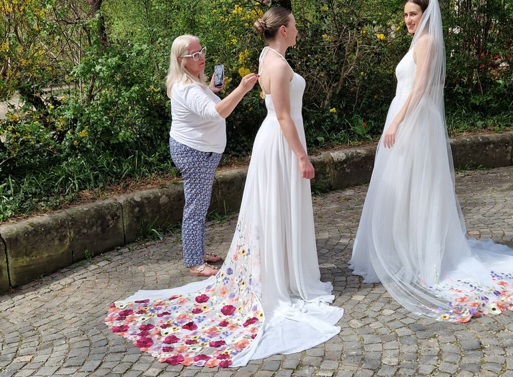 Brautkleider Nürnberg – zwei Bräute mit floraler Schleppe im Freien, Bella Sposa Brautmode