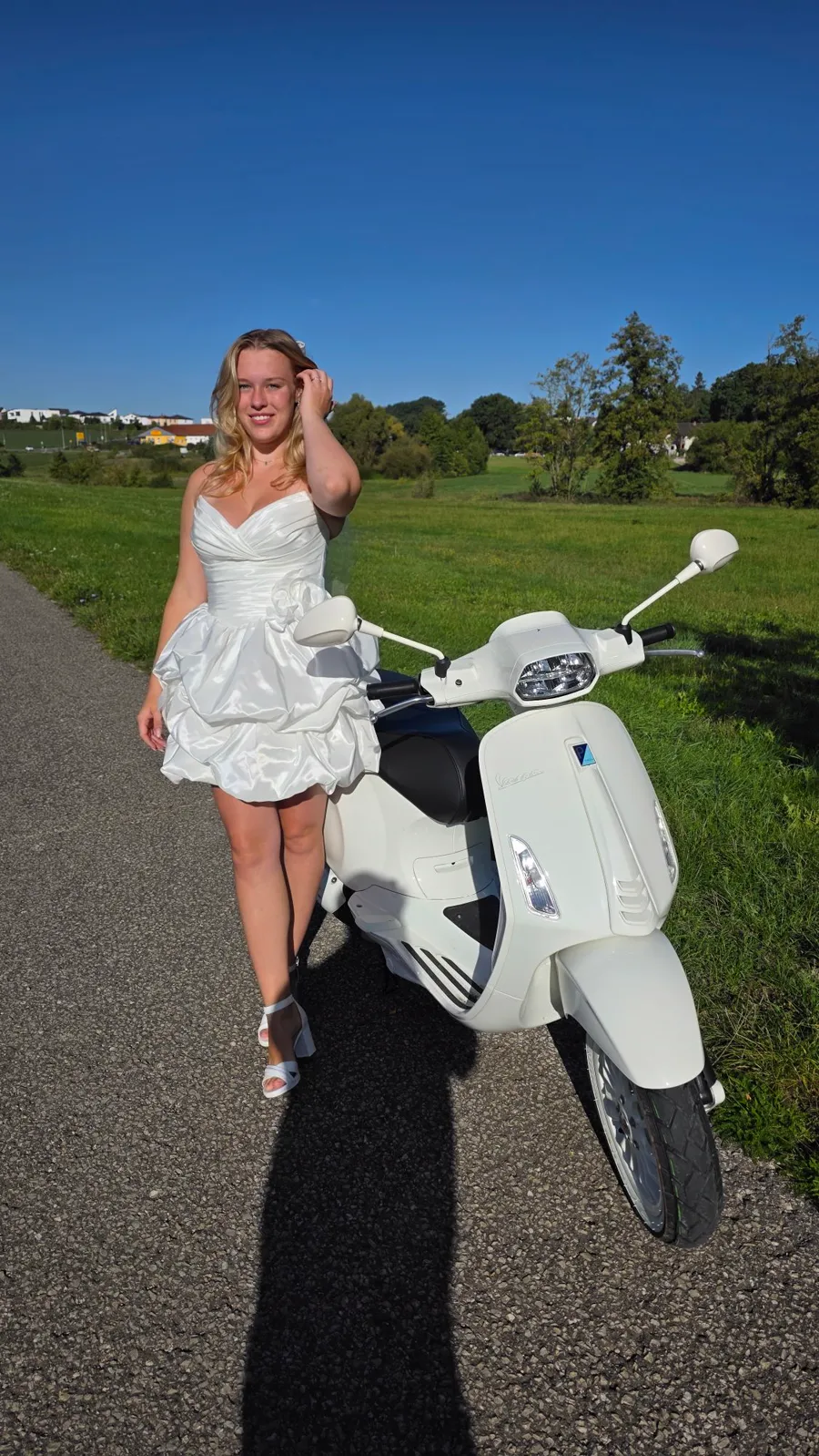 Braut im kurzen Satin-Brautkleid neben einer weißen Vespa, Standesamt-Look von Bella Sposa