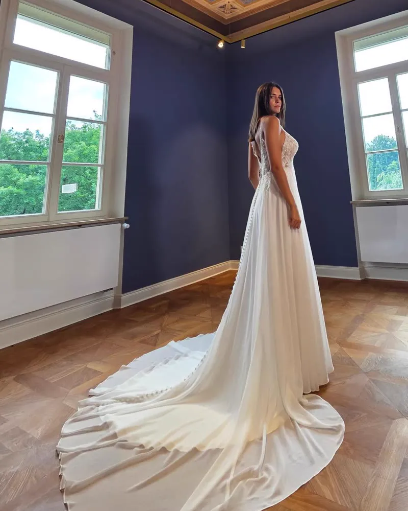 Braut im fließenden Brautkleid mit langer Schleppe in einem historischen Saal