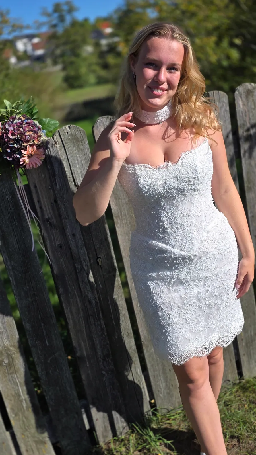 Kurzes Spitzen-Brautkleid mit Perlen am Holzzaun