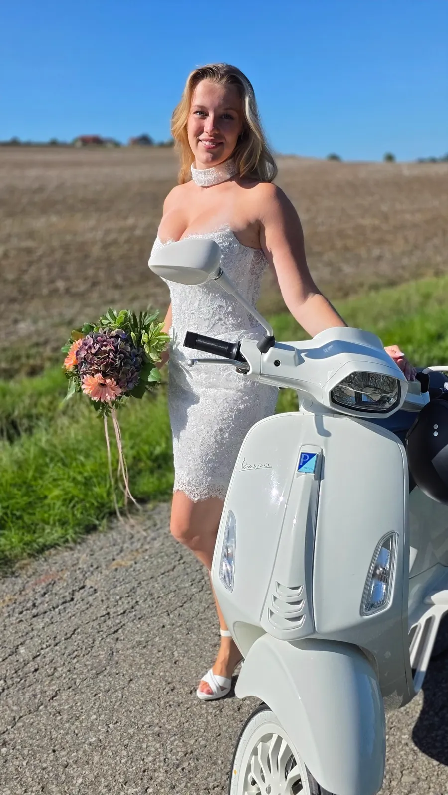 Kurzes Spitzen-Brautkleid mit Halsband und Brautstrauß neben einer Vespa